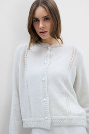 A delicate buttoned cardigan made of ecru alpaca wool and girl's wool.